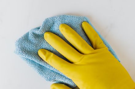 Crop unrecognizable person in yellow gloves cleaning white surface